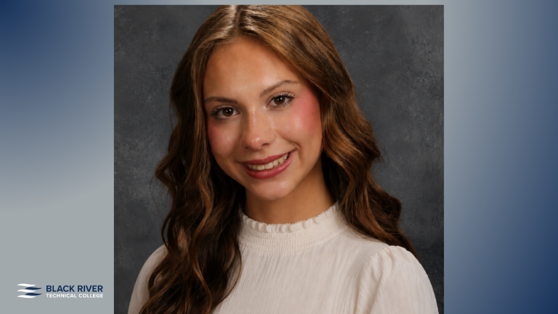 A young woman with long wavy brown hair and highlights, wearing a white blouse, smiles for a studio portrait against a gray backdrop, with Black River Technical College branding.